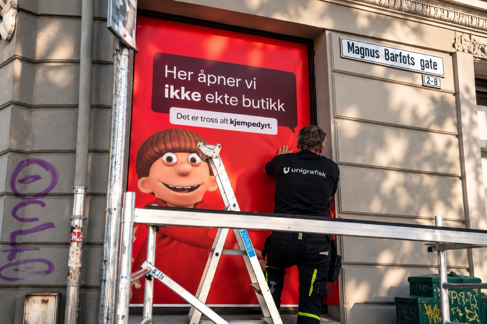 Montør på stige ved et foliert butikkvindu