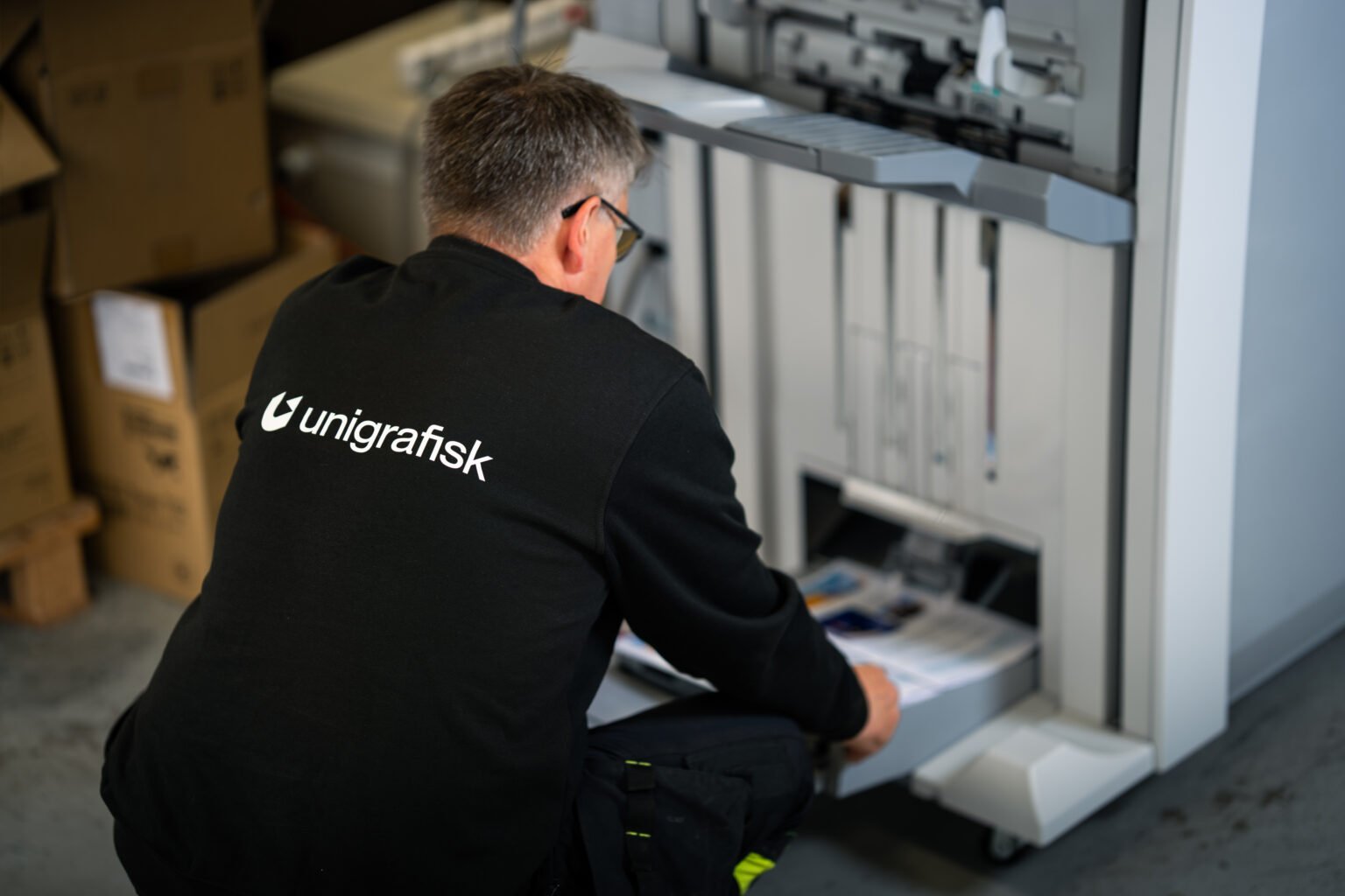 Ansatt henter ark fra digitaltrykkmaskinen